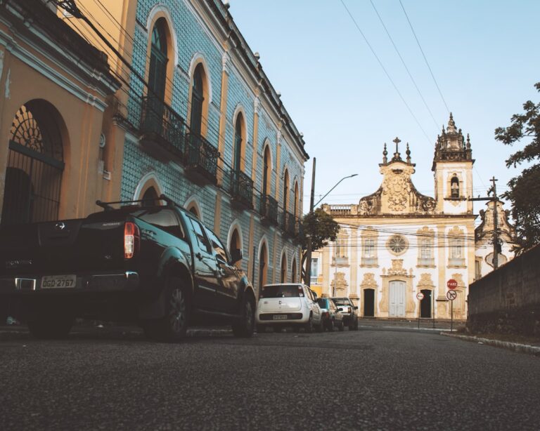Um Grupo De Carros Estacionados Ao Lado De Uma Rua VzemllwNVho