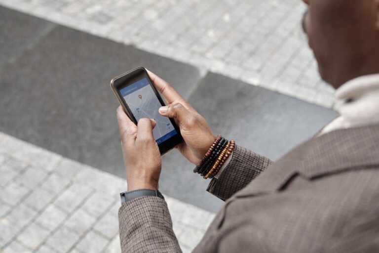 A stylish professional adult using a smartphone with a navigation app on an urban street.