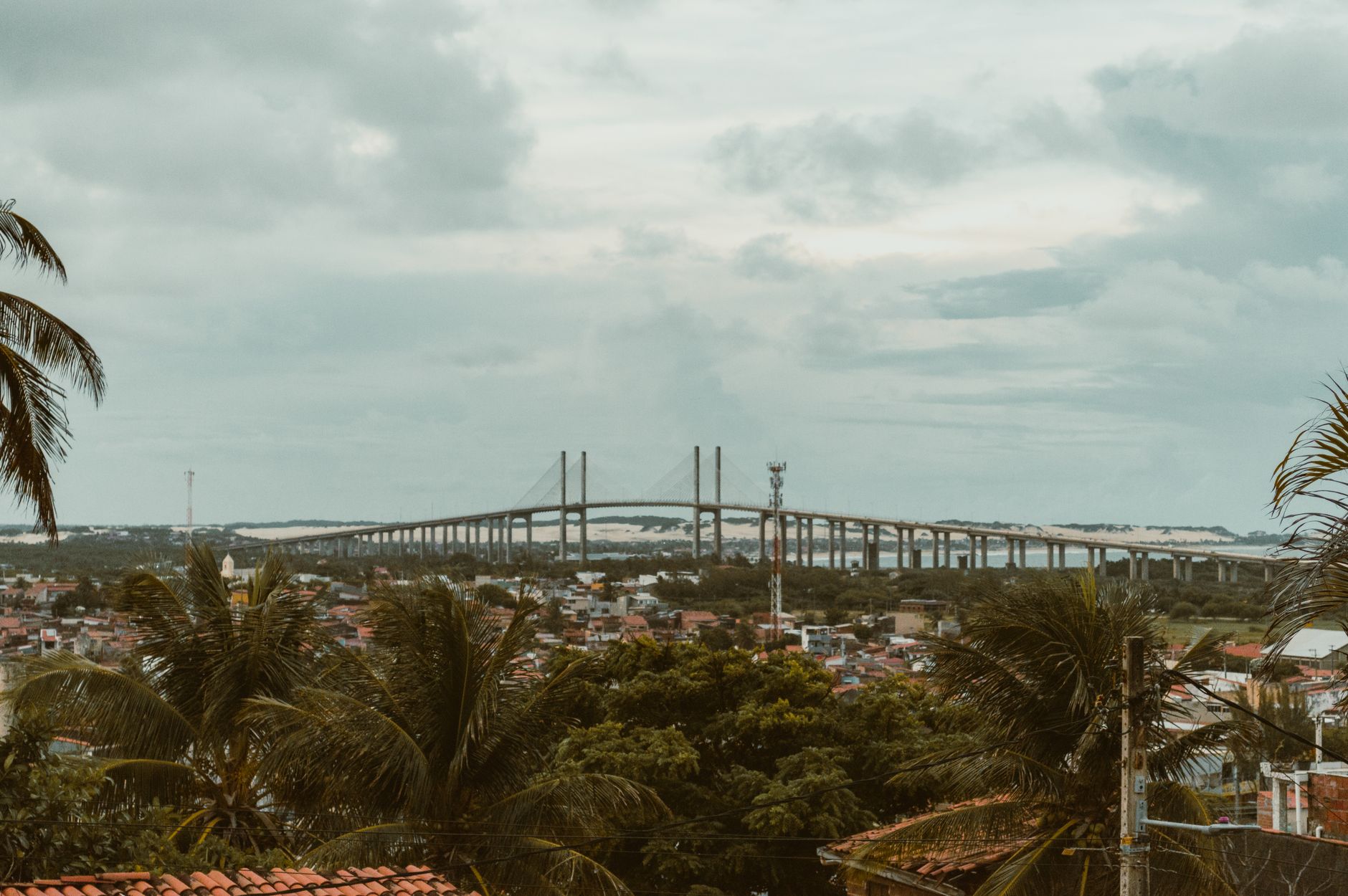 Scenic view of Newton Navarro Bridge over Natal cityscape with cloudy sky and lush greenery.