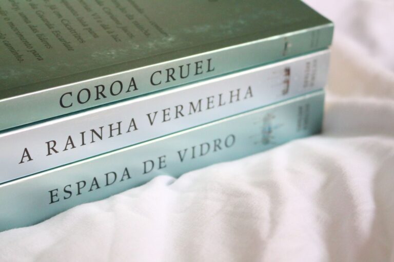 Three novels with Portuguese titles neatly stacked on a soft white background.